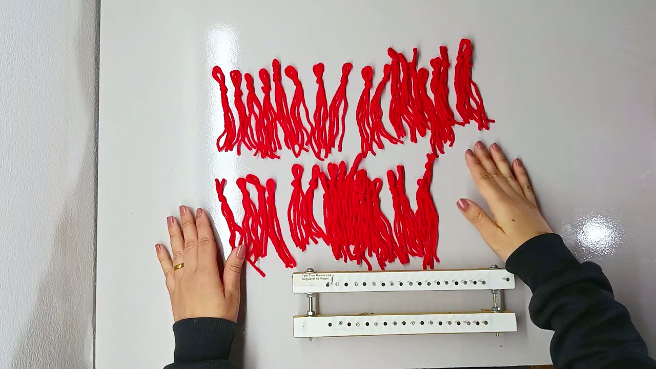 Franjas de lã vermelha prontas ao lado do tear de cachecol