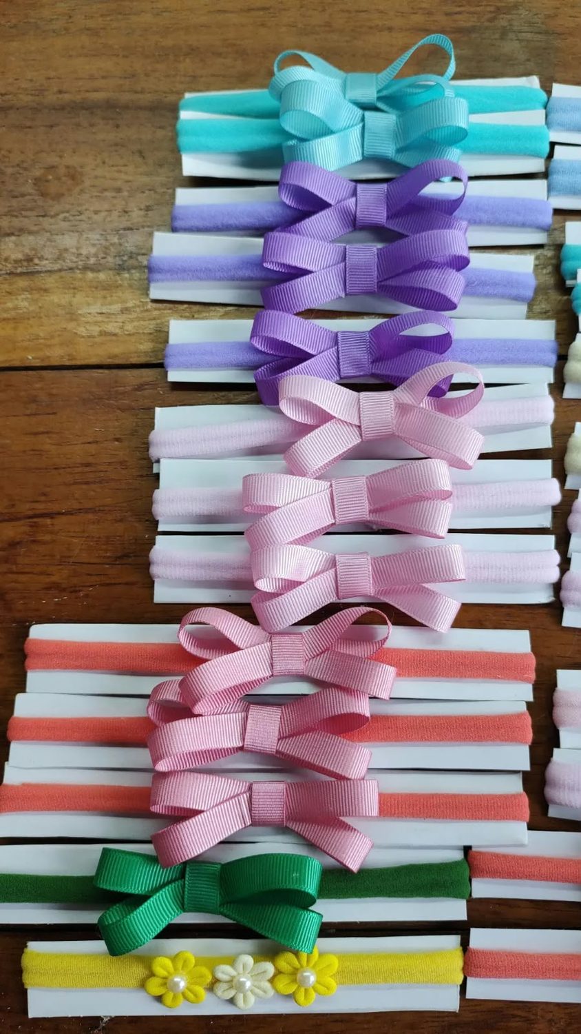 Fileira de faixas com laços em lilás, rosa e verde